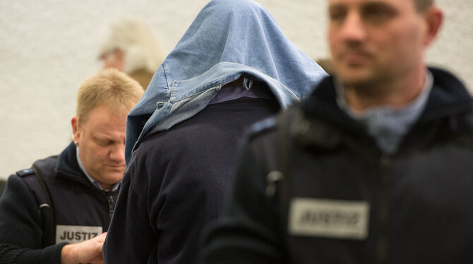Der Angeklagte im Koffermord-Prozess, Günter H., der Handschließen und eine Jacke über dem Kopf trägt. Foto: Marijan Murat/dpa
