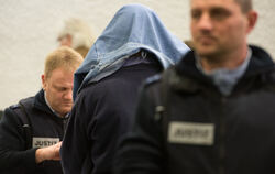 Der Angeklagte im Koffermord-Prozess, Günter H., der Handschließen und eine Jacke über dem Kopf trägt. Foto: Marijan Murat/dpa