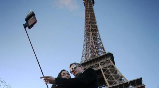 Ein Paar macht unter dem Eiffelturm ein paar Selfies. Foto: Fredrik von Erichsen/Archiv