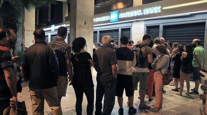 Nach der Tsipras-Ansage noch schnell zum Geldautomaten. Menschen stehen in Athen Schlange vor einer Bank. Foto: Simela Pantza