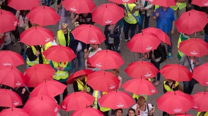 Demonstranten mit roten Regenschirmen in Hamburg während einer Aktion der Gewerkschaft Verdi unter dem Motto "Tarifverträge s