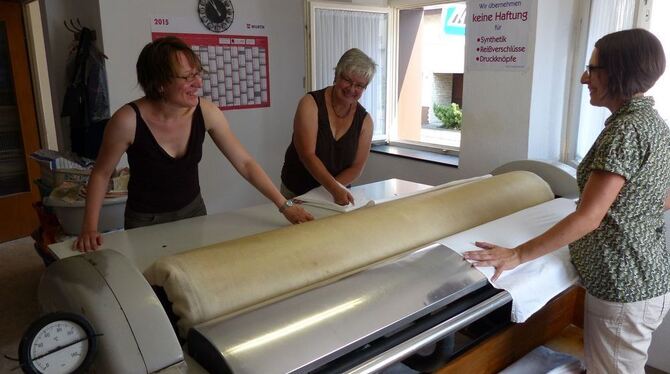 Annemarie Neth wird an der Heißmangel von ihren Töchtern Susanne Neth (links) und Kerstin Kern unterstützt. Heute, Freitag, schl