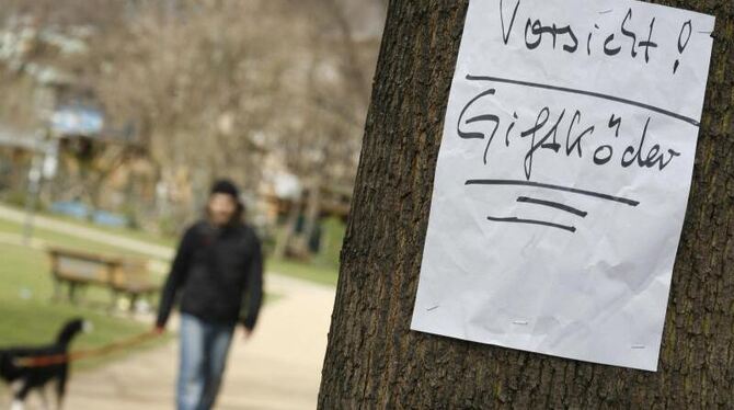 Ein Zettel warnt in einem Park vor ausgelegten Giftködern