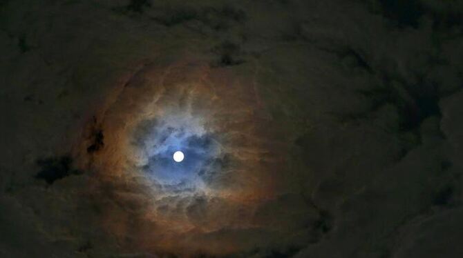 Der nahezu volle Mond scheint durch eine Wolkenlücke. Foto: Karl-Josef Hildenbrand