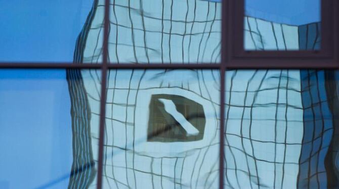 Verzerrt spiegelt sich in Frankfurt am Main das Logo der Deutschen Bank in einer Glasfassade. Foto: Frank Rumpenhorst/Illustr