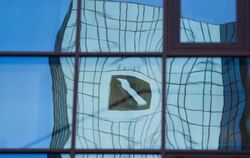 Verzerrt spiegelt sich in Frankfurt am Main das Logo der Deutschen Bank in einer Glasfassade. Foto: Frank Rumpenhorst/Illustr