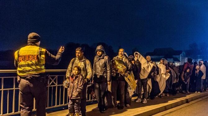 Ein Polizist nimmt bei Simbach am Inn an der deutsch-österreichischen Grenze eine Gruppe von Flüchtlingen in Empfang. Foto: A