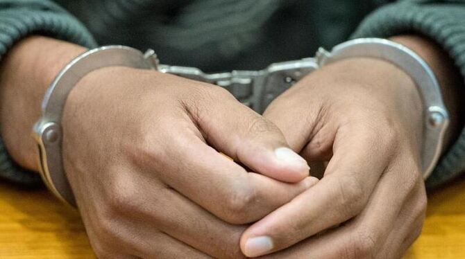 Ein mit Handschellen gefesselter Angeklagter. Der Mann wurde beschuldigt, Teil einer Schleuserbande gewesen zu sein. Foto: Bo