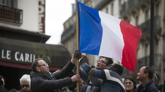 Pariser stellen in der Nähe einer der Anschlagsorte eine französische Fahne im Gedenken an die Opfer auf.