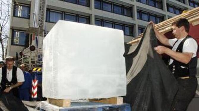 Zimmerleute stülpen das von ihnen gebaute &raquo;Passivhaus&laquo; sorgsam über den Eiswürfel, den sie zuvor in schwarzes Tuch g