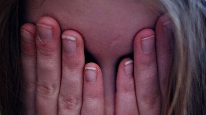 Ein Mädchen hält sich die Hände vor das Gesicht.  FOTO: DPA