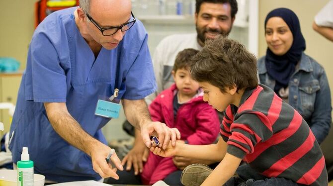 Ein syrischer Flüchtlingsjunge stempelt zusammen mit eine Arzthelfer seinen Impfausweis (Archivbild).