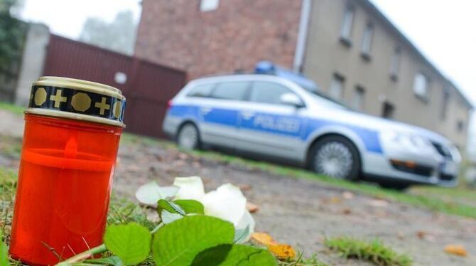 Eine Kerze, eine Blume und ein Polizeiwagen: Das Haus des mutmaßlichen Entführers und Mörders des Flüchtlingskindes Mohamed.