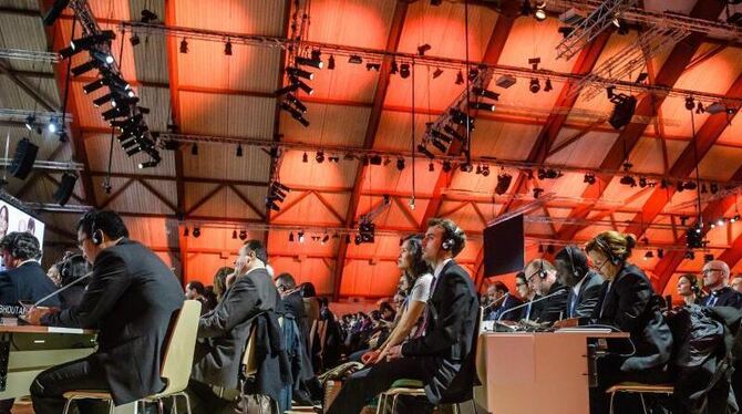 Delegierte der UN-Klimakonferenz lauschen der Rede von Laurent Fabius. Foto: Christophe Petit Tesson