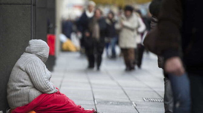 ARCHIV. Eine Obdachlose sitzt in Stuttgart auf dem Boden einer Einkaufsstraße. Foto: Daniel Naupold/dpa