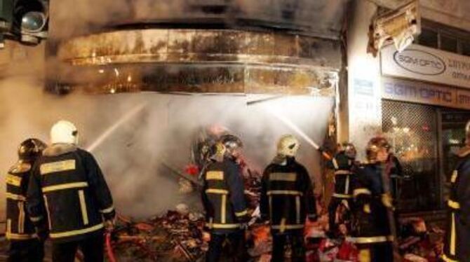 Die Feuerwehr versucht, ein brennendes Geschäft in Athen zu retten. FOTO: DPA