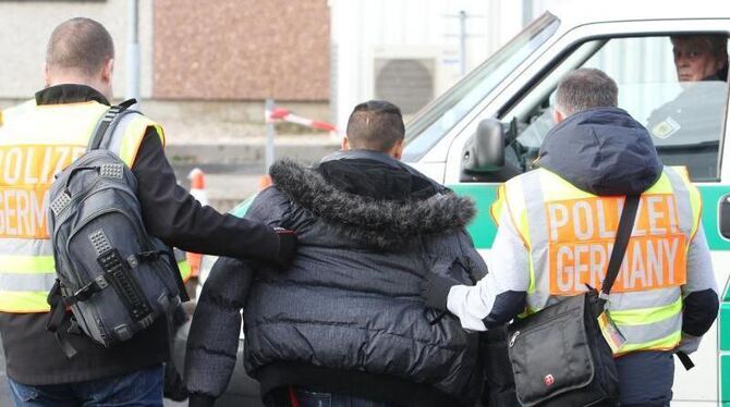 Polizisten begleiten einen straffällig gewordenen Asylbewerber zu seinem Abflug. Foto: Sebastian Willnow/Archiv