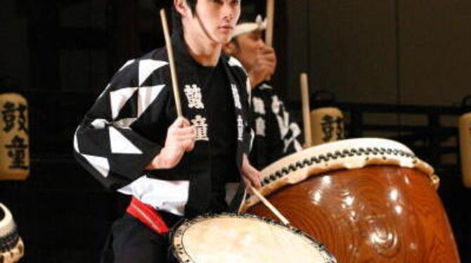 Vorne ein Kodo-Musiker an einer leichten Trommel koreanischer Herkunft (&raquo;Oke-daiko&laquo;), dahinter ein Spieler an einer