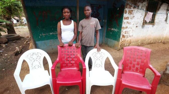 Lorpu Kollie (l) und ihr Bruder Anthony (r) leben im liberianischen Monrovia. Die leeren Stühle symbolisieren Verwandte, die