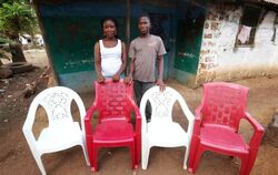 Lorpu Kollie (l) und ihr Bruder Anthony (r) leben im liberianischen Monrovia. Die leeren Stühle symbolisieren Verwandte, die 