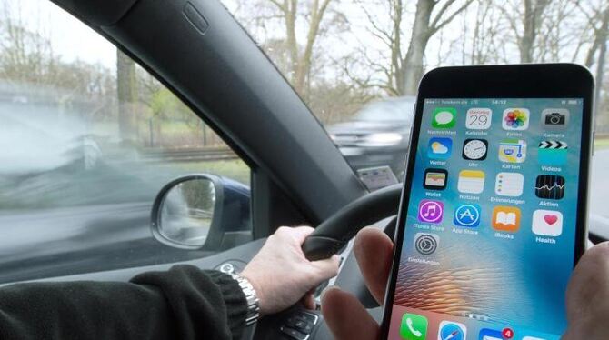 Eine Hand am Smartphone, die andere am Lenkrad - wohl eine der Hauptursachen für Unfälle. Foto: Sebastian Gollnow / Illustrat