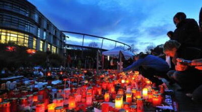 Trauernde Fans stehen vor der AWD-Arena vor brennenden Kerzen.
FOTO: DPA