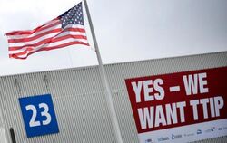 Eine amerikanische Flagge weht auf dem Gelände der Hannover Messe vor einem Plakat mit der Aufschrift «Yes - We want TTIP». F