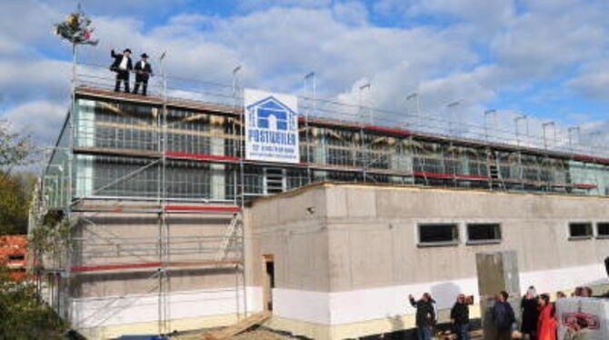 Die Zimmerleute Kai Schreckenbach und Christian Kleine beim Richtspruch auf dem Dach der Firstwald-Sporthalle.
GEA-FOTO: MEYER