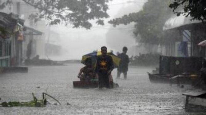 Philippiner waten durch von Taifun »Parma« überflutete Straßen.
FOTO: DPA