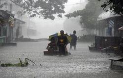 Philippiner waten durch von Taifun "Parma" überflutete Straßen.
FOTO: DPA