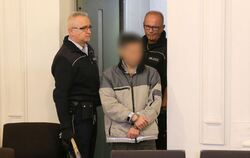 In Handschellen wird der Angeklagte in einen Saal des Landgerichtes Karlsruhe geführt.