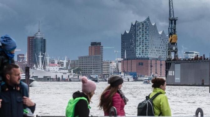 Bei 10 Grad Lufttemperatur und vereinzelten Schauern gehen Passanten in Hamburg an der Elbe entlang. Foto: Markus Scholz
