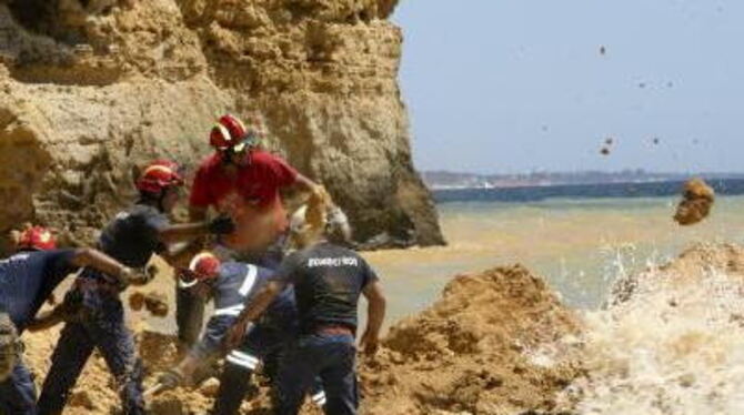 Nach dem Felssturz: Feuerwehrleute suchen am Strand von Albufeira nach Verschütteten.
FOTO: DPA