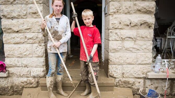 Die fleißigen Helfer Carolin (12) und Florian (8) stehen bei Aufräumarbeiten nach dem schweren Unwetter in Braunsbach vor dem Ge Die fleißigen Helfer Carolin (12) und Florian (8) stehen bei Aufräumarbeiten nach dem schweren Unwetter in Braunsbach vor dem Ge