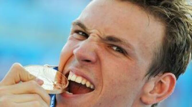 Paul Biedermann beißt nach seinem Sieg über 200 Meter Freistil in seine Goldmedaille.
FOTO: DPA