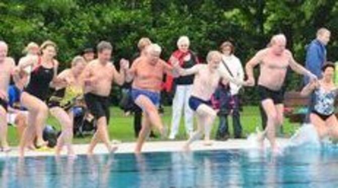 Hand in Hand ins Wasser: Lokalprominenz und Bürger springen gemeinsam vom Beckenrand aus ins Schwimmerbecken. Der Schwimmmeister