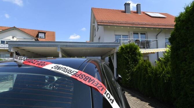 Ein Absperrband der Polizei liegt in Unterschach bei Ravensburg auf einem Auto vor dem Haus, in dem ein Mann seine Frau und sein