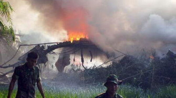 Das brennende Wrack des Militärtransporters liegt in einem Reisfeld. FOTO: DPA