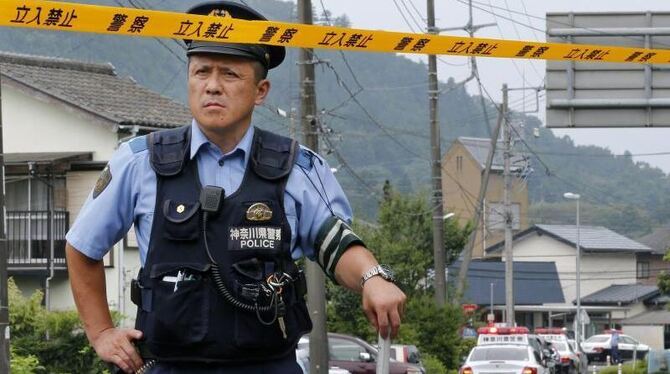 Ein Polizist sichert die Straße zum Tatort. foto: Kimimasa Mayama