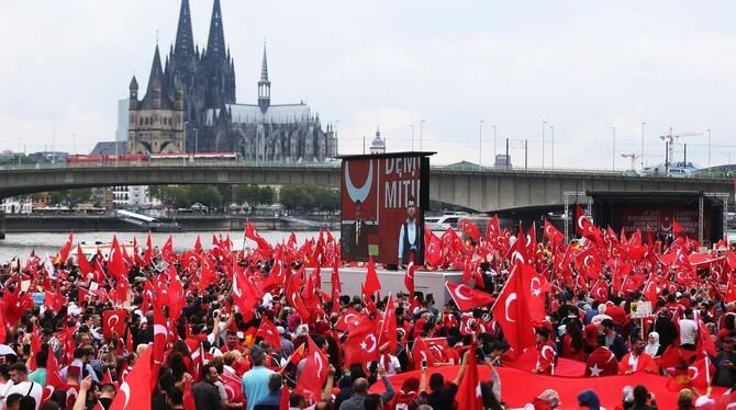 Anhänger des türkischen Staatspräsidenten Erdogan schwenken in Köln türkische Fahnen.