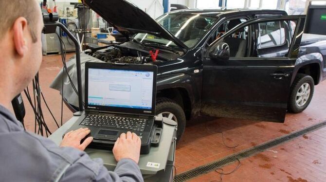 Ein Kfz-Meister lädt im Rahmen der Rückrufaktion zum Abgasskandal ein Software-Update in einer Volkswagen-Werkstatt. Foto: Ju
