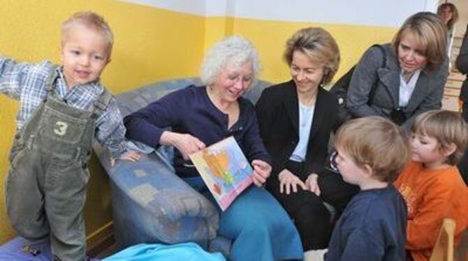 Ingeborg Bornhak (links) liest aus einem Buch vor, Ursula von der Leyen (Mitte) und Annette Widmann-Mauz hören bei ihrem Besuch