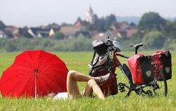 Eine Radtouristin macht am auf einer Wiese am Donau-Radwanderweg bei Daugendorf eine Pause. Foto: Thomas Warnack